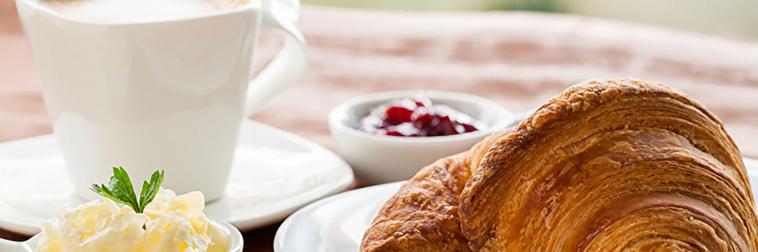 Frühstück mit Kaffe, Croissant, Butter und Kirschmarmelade